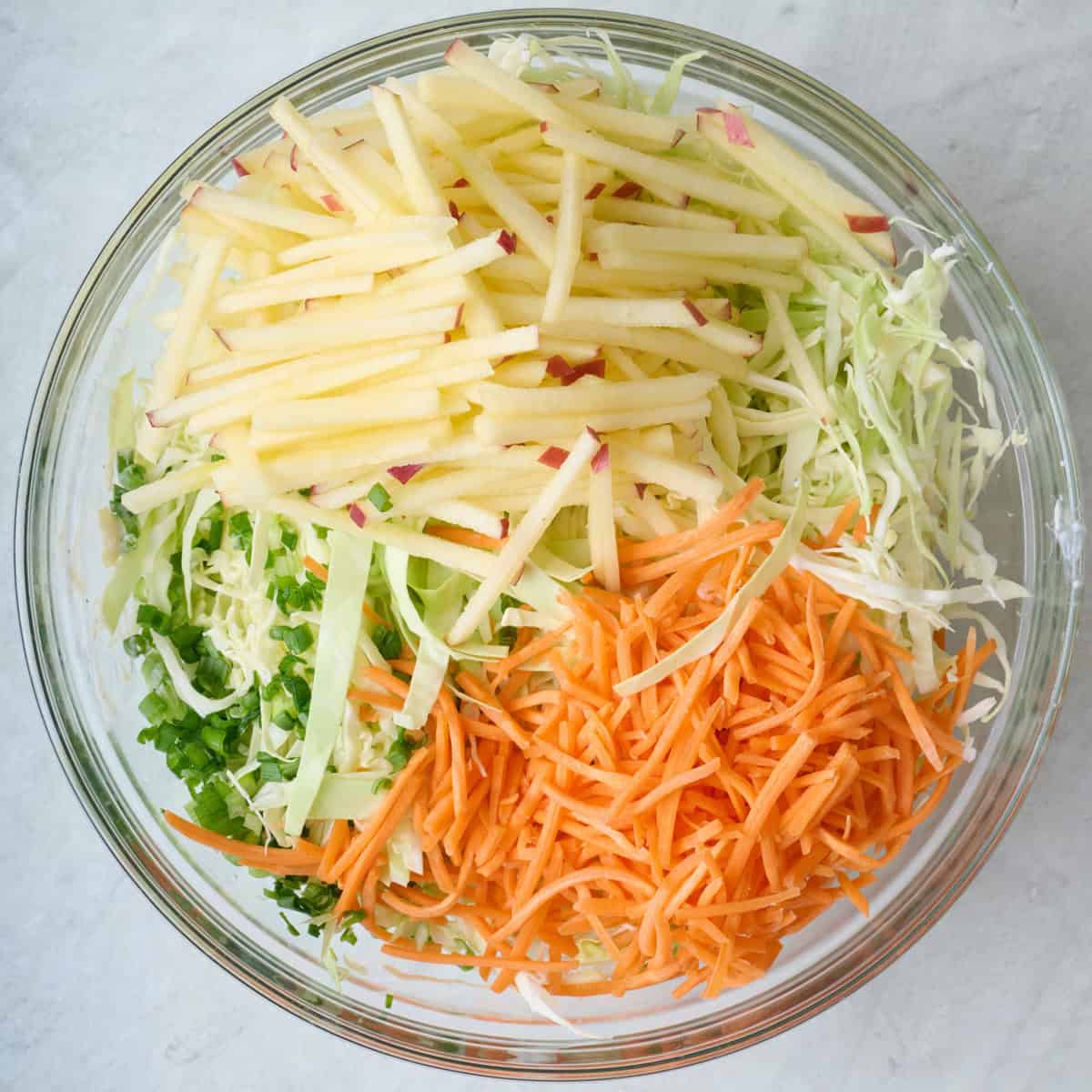 Fresh cut veggies added to bowl on top of dressing.