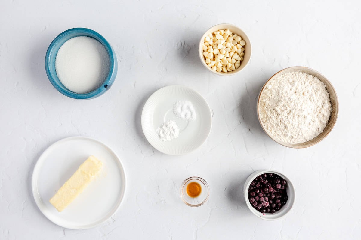 Ingredients for recipe: sugar, butter, baking powder salt, white chocolate chips, flour, vanilla extract, and frozen blueberries.