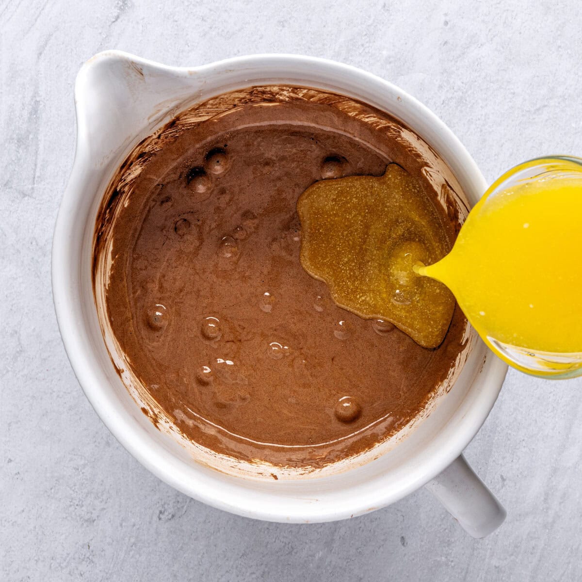 Brownie mixture after combining with melted butter being poured in.
