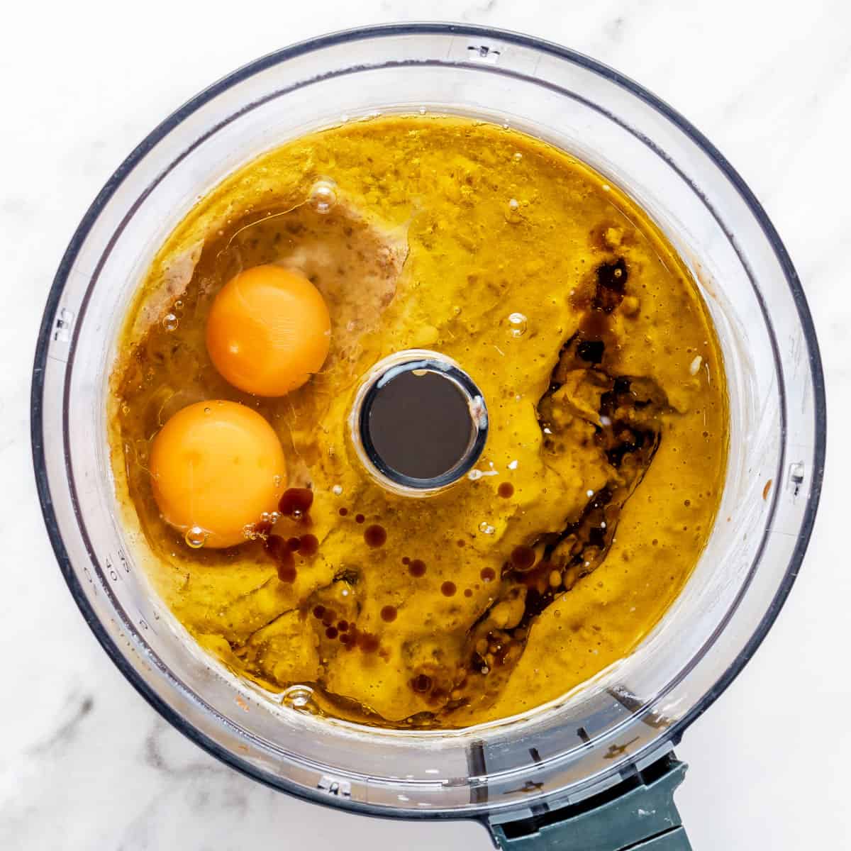 Eggs, vanilla, and oil added to food processor on top of blended dates.