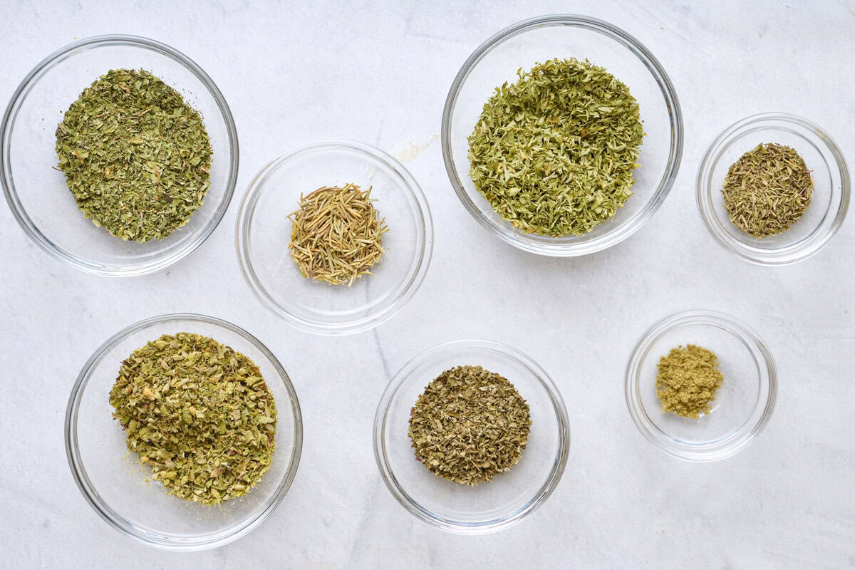 Dried herbs in separate bowls for the ingredients for recipe.