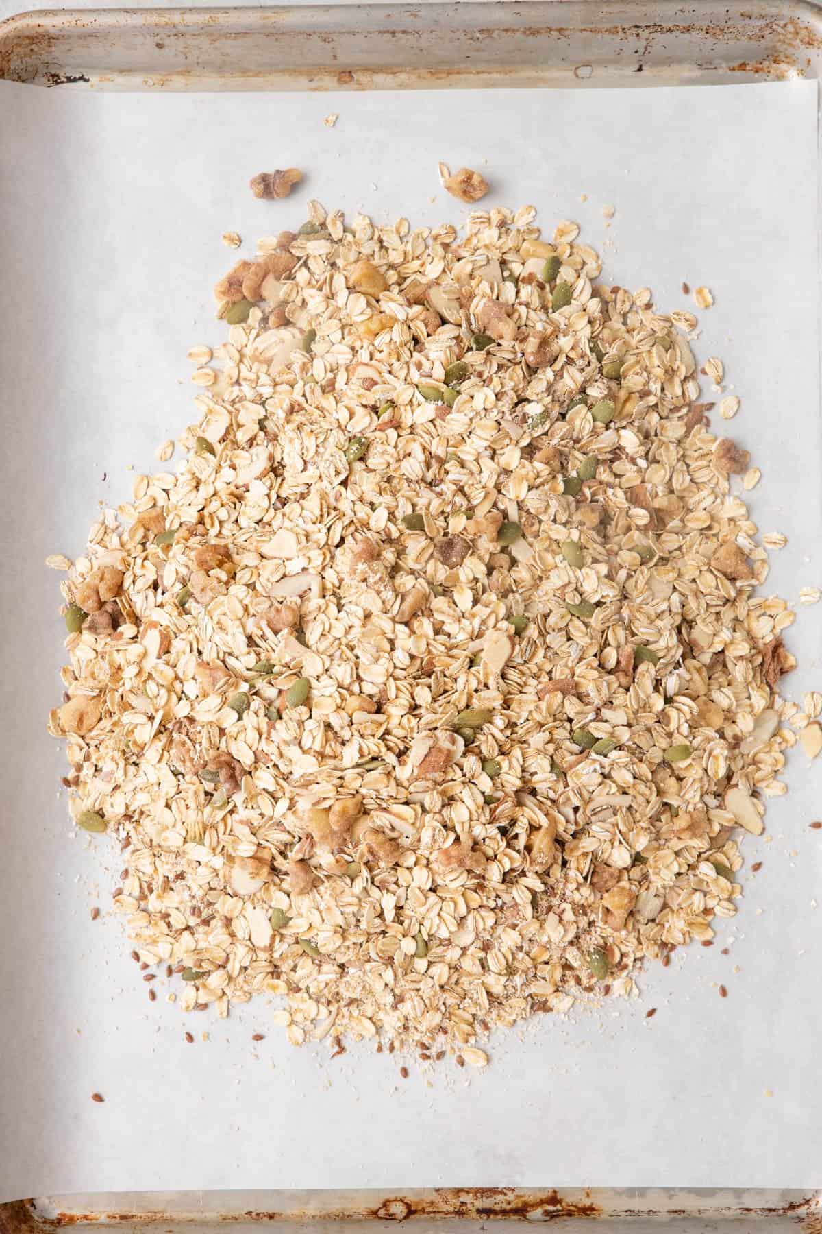 Oats, wheat bran, nuts, seeds, cinnamon and salt on a large baking sheet.