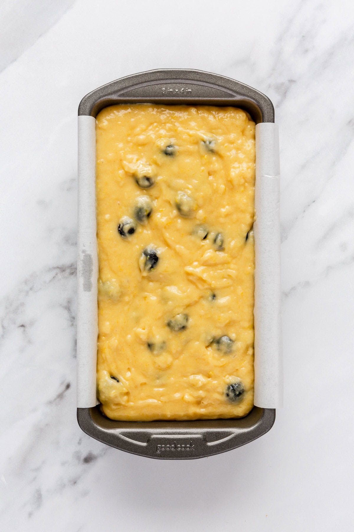 Bread batter in a parchment lined loaf pan before baking.