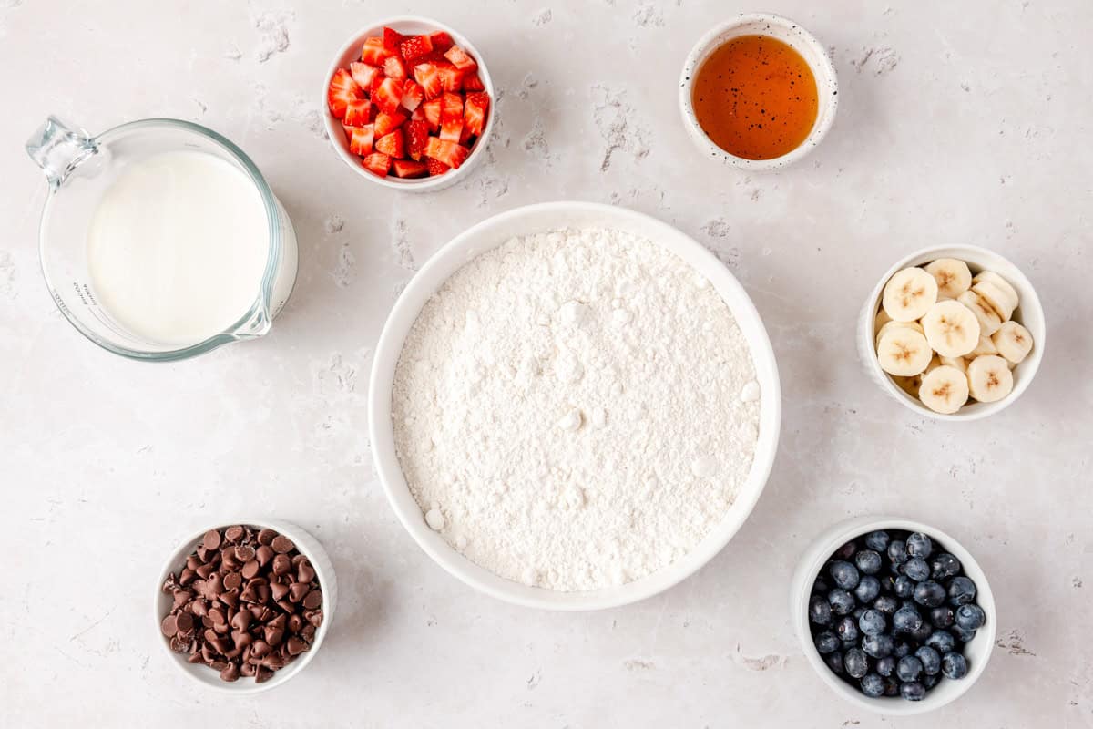 Ingredients for recipe plus optional toppings: milk, pancake mix, honey, plus strawberries, blueberries, bananas, and chocolate chips.