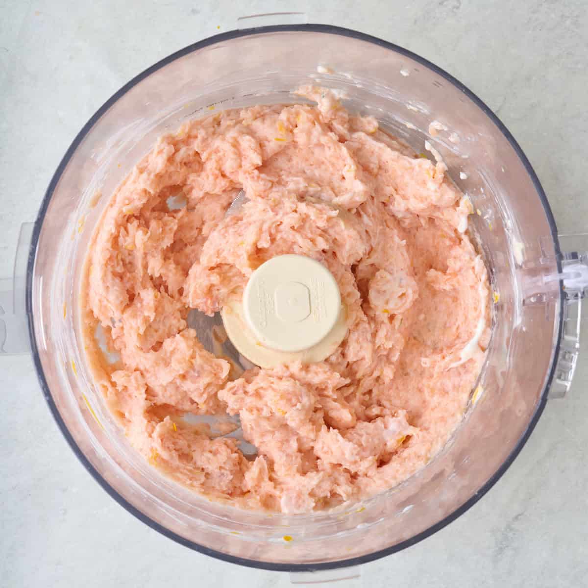 A blended salmon, yogurt, and mustard mixture in the bowl of a food procesor.