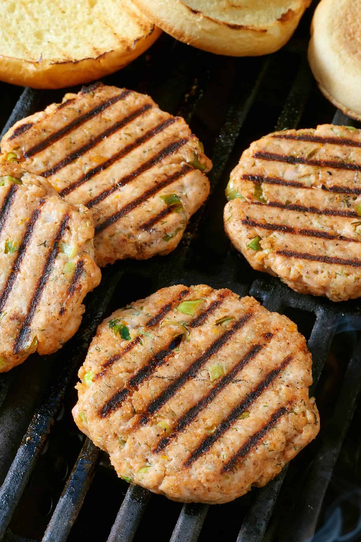 Salmon burgers cooking on a grill.
