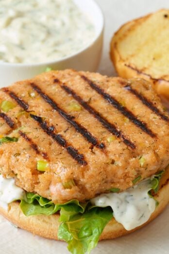 Grilled salmon burger patty on a bun with toppings.