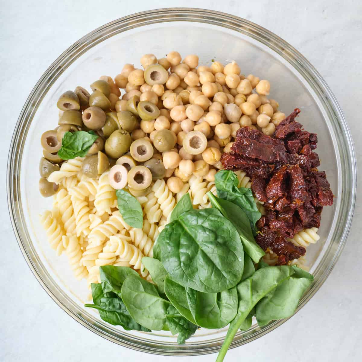 Cooked pasta, chickpeas, olives, spinach and sun dried tomatoes added on top of dressing.