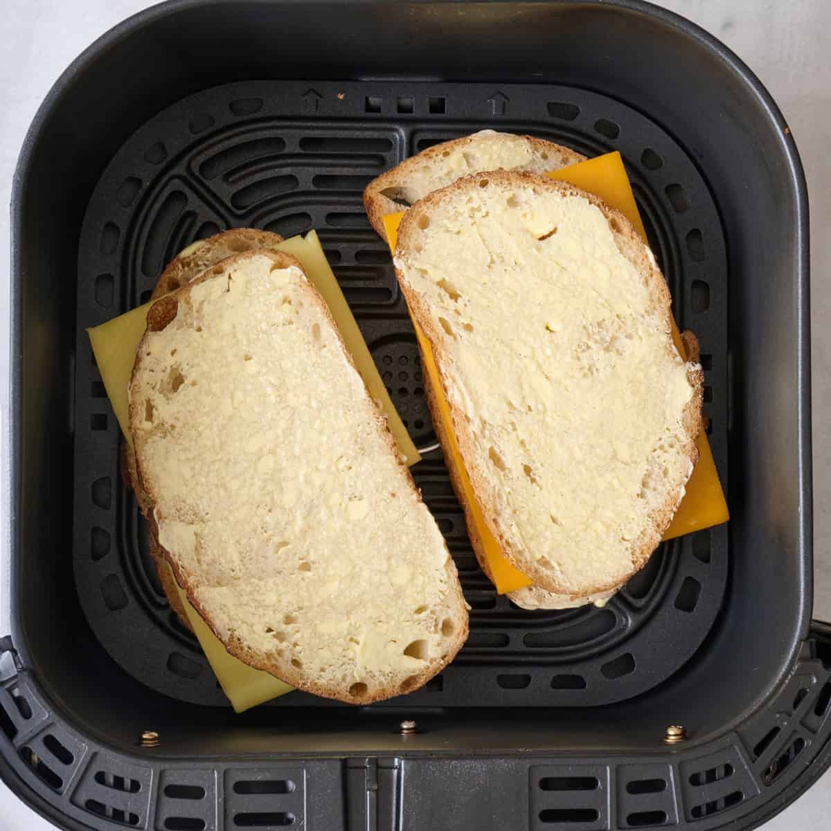 2 sandwiches in an air fryer basket before cooking.