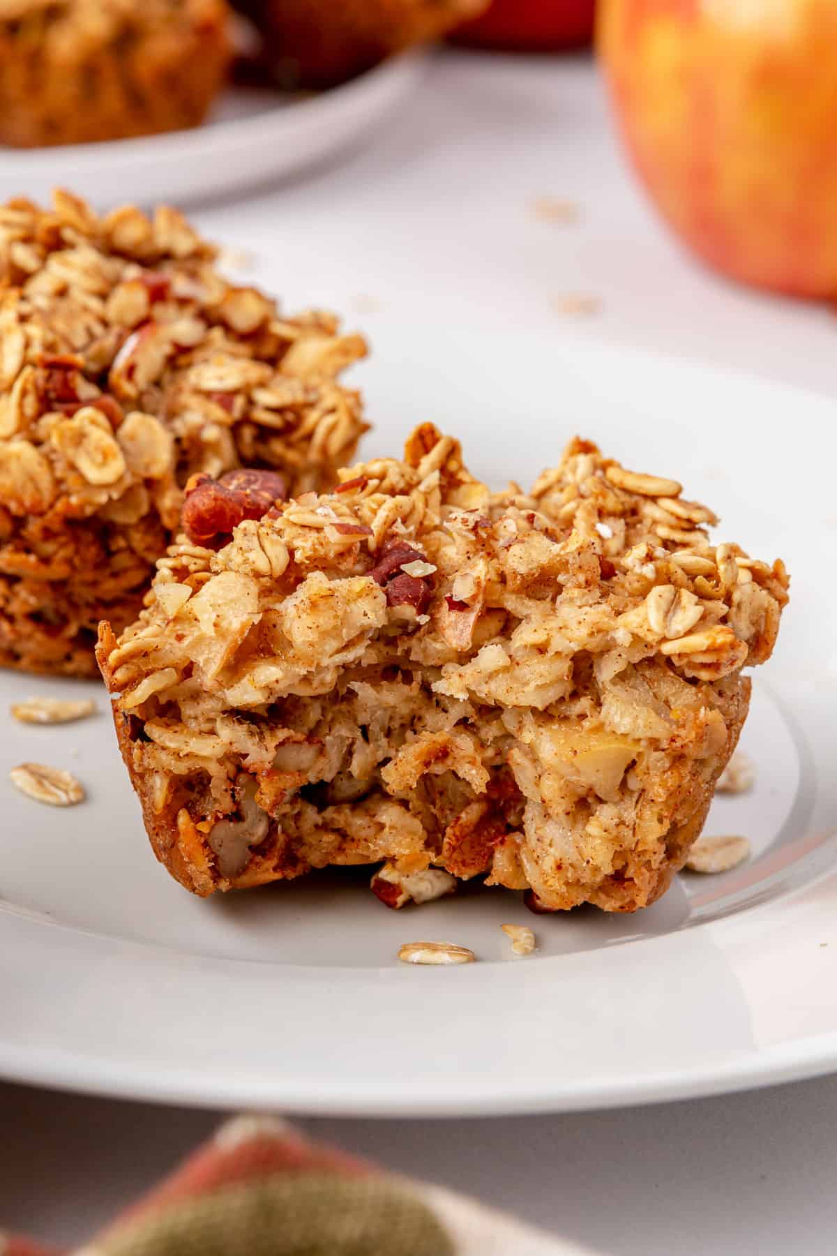 Two apple cinnamon oatmeal cups on a plate with a bite taken out of one.