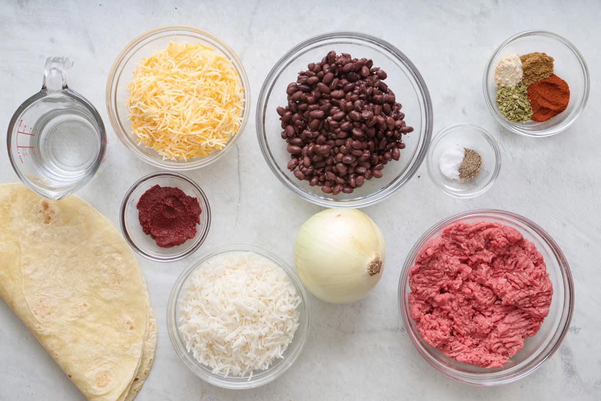 Ingredients for recipe: cheese, tomato paste, flour tortillas, black beans, onion, spices, and ground beef.