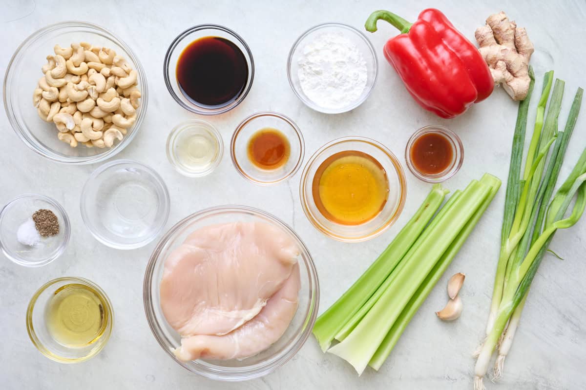 Ingredients for recipe: honey, soy sauce, sesame seed oil, rice vinegar, sriracha sauce, chicken, salt pepper, cornstarch, avocado oil, green onions, garlic cloves, ginger, red pepper, celery stalks, and roasted cashews.