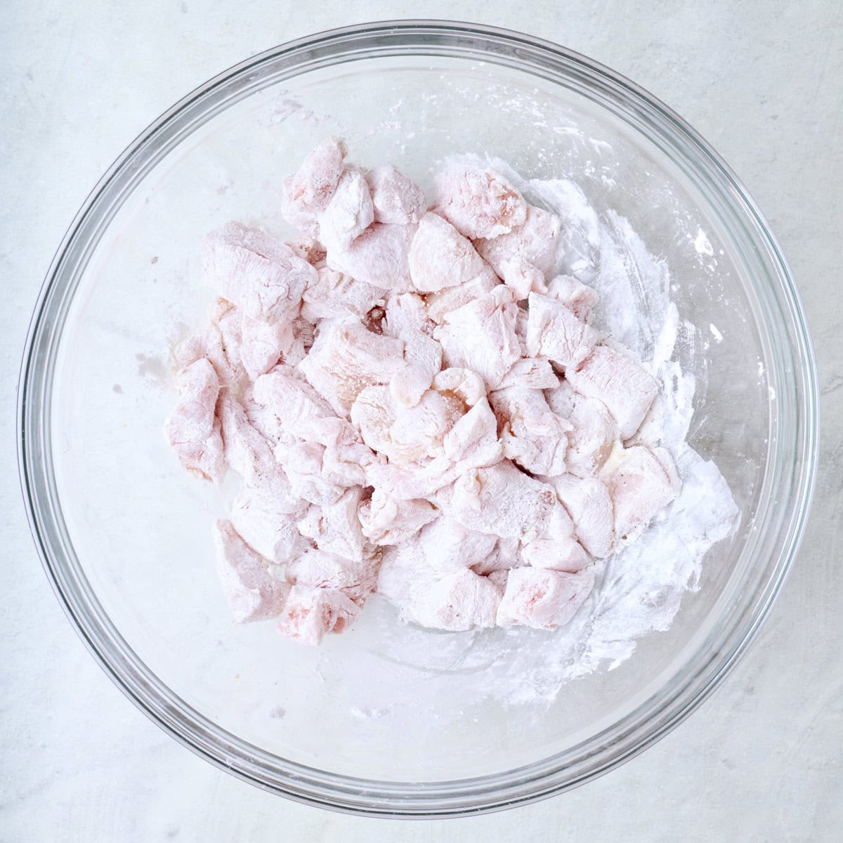 Corn starch coated chicken pieces in a bowl.