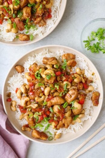 Two bowls of cashew chicken over rice, chop sticks nearby.