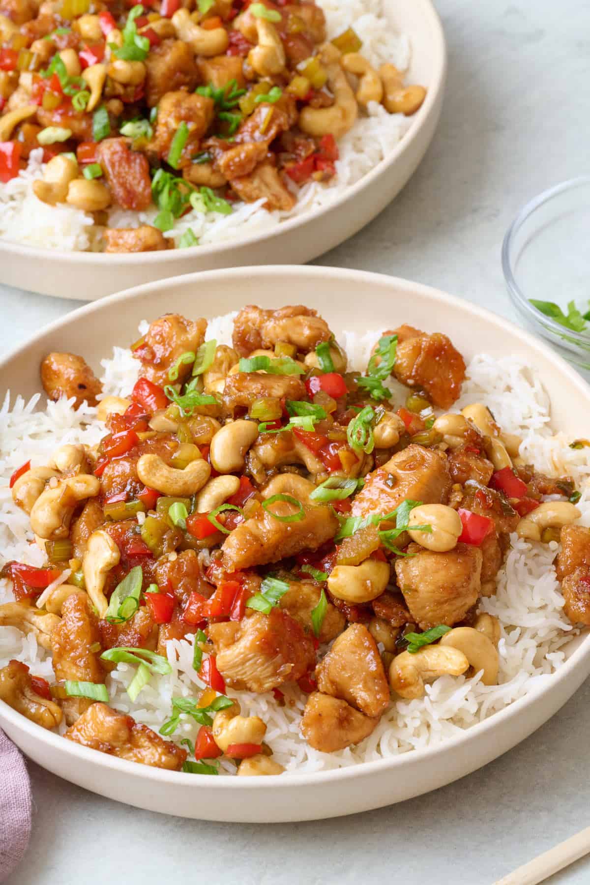 Bowl of rice with cashew chicken on top and another bowl nearby.