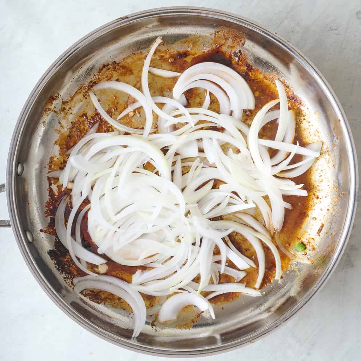 Onions added to pan after removing cooked chicken.