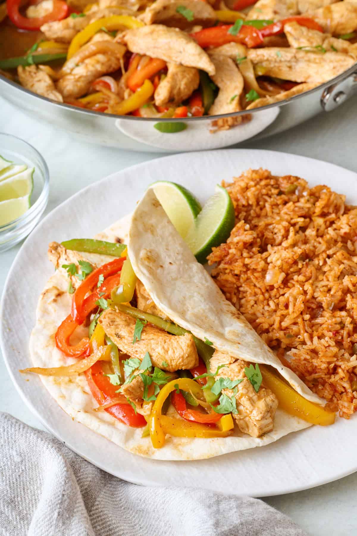 Chicken fajita filling in a flour tortilla on a plate with Spanish rice.