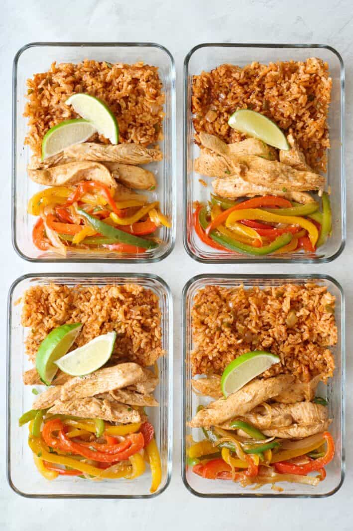 Chicken fajitas bowl divided into 4 meal prep containers with lemon, chicken, peppers, and onions.