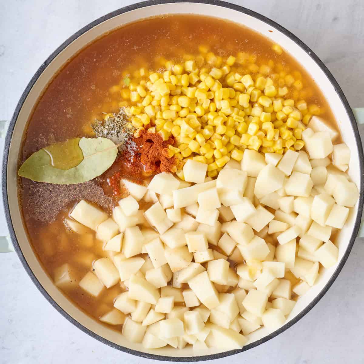 Broth, potatoes, corn and seasonings added before stirring.