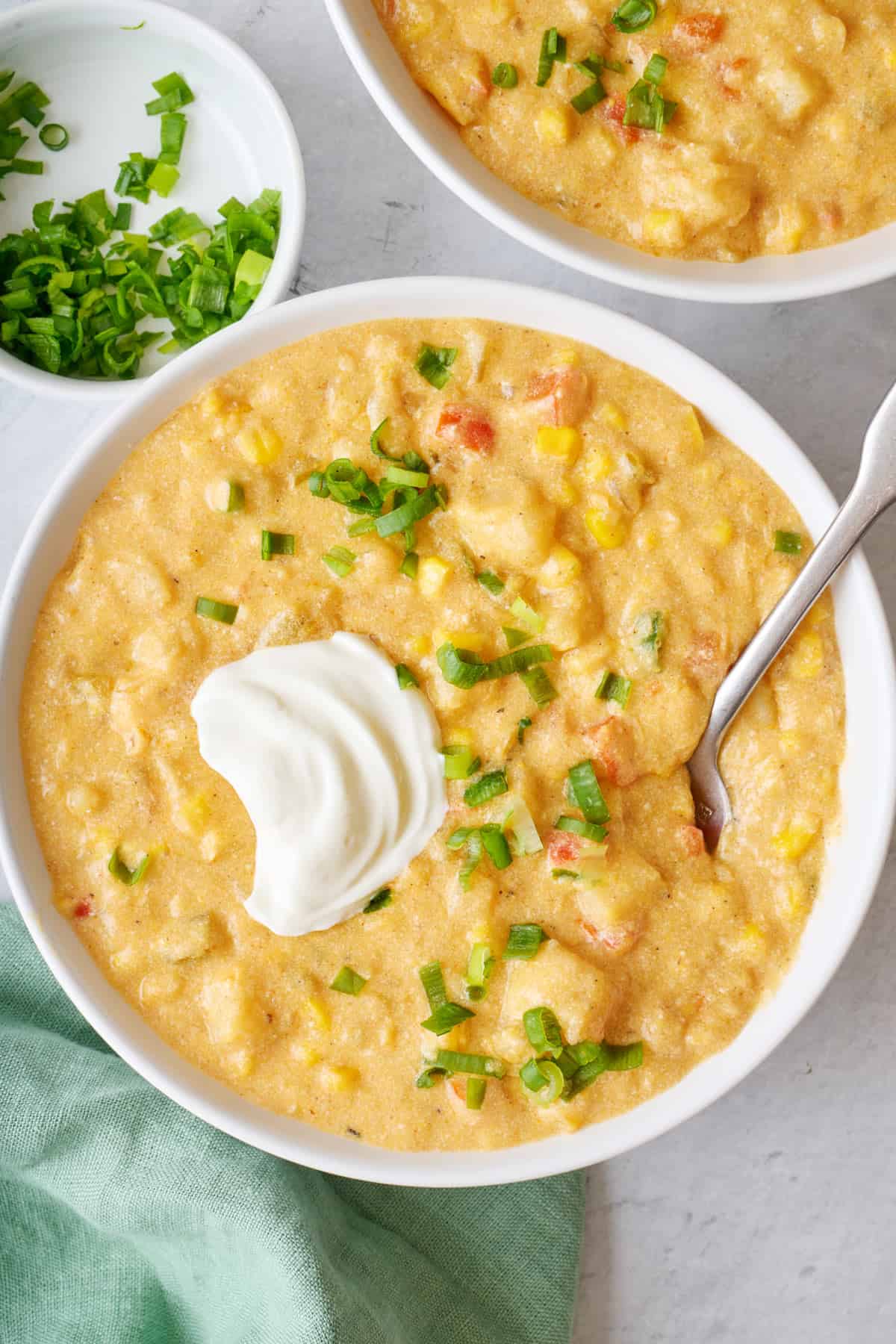 Closer shot on one bowl of vegetarian corn chowder with a small dollop of Greek yogurt added on top and spoon dipped inside bowl