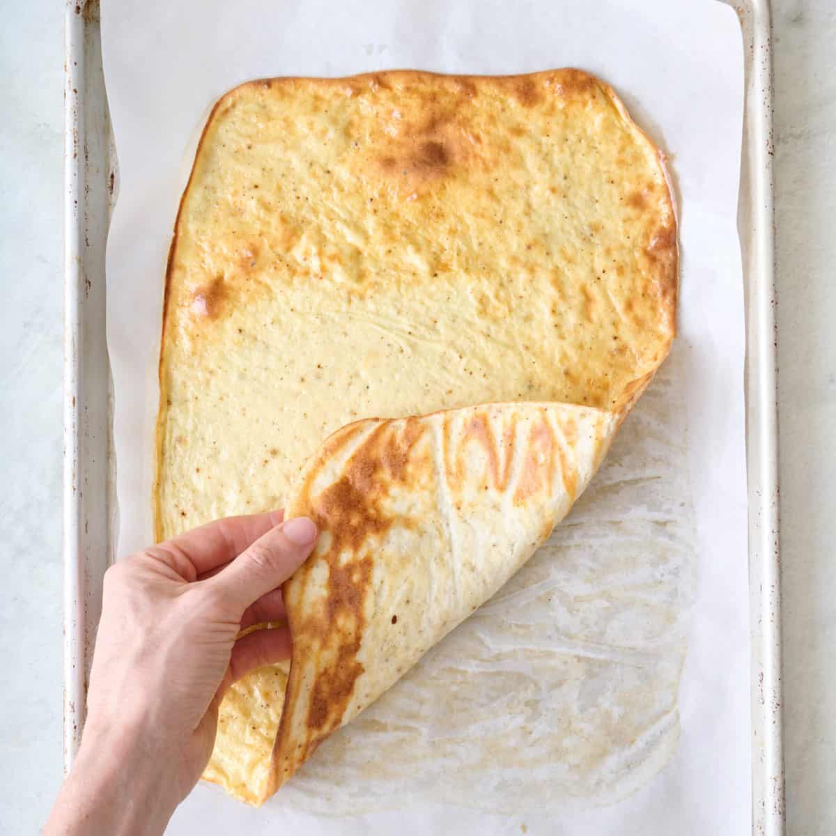 Hand lifting up edge of baked flat bread.