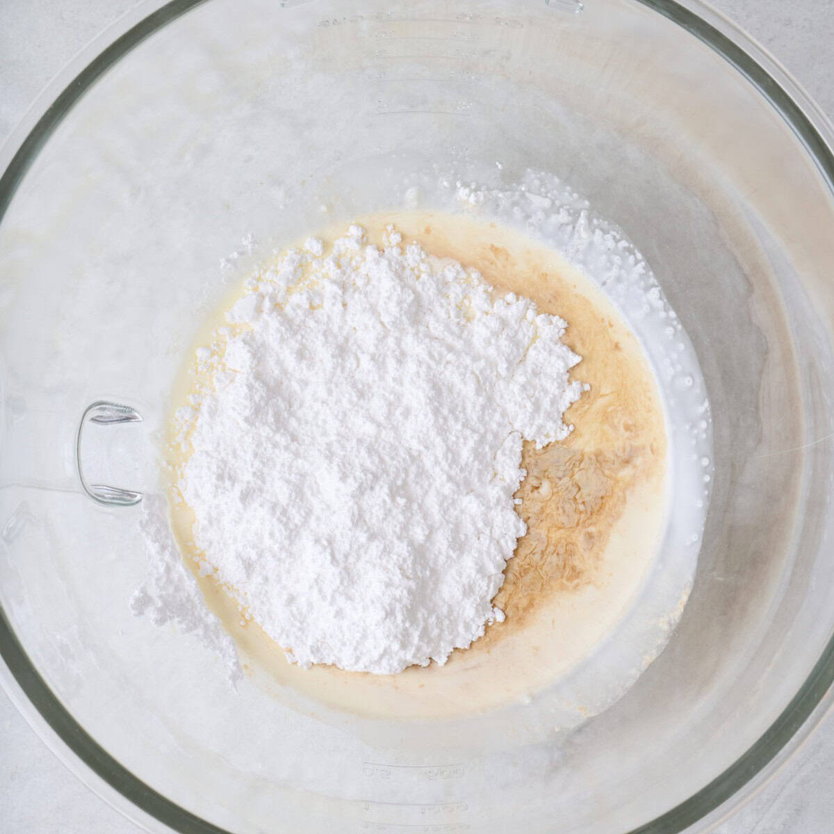 Heavy cream, powdered sugar, and vanilla in the bowl of a stand mixer before mixing.