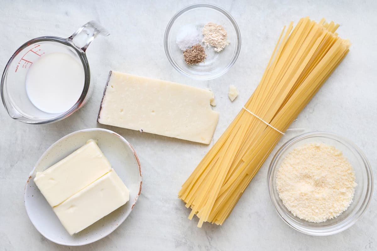 Ingredients for recipe before prepping: milk, butter, parmesan, seasonings, and pasta.