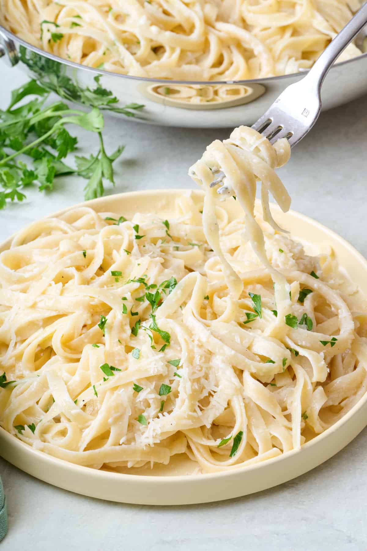 Fork lifting up a bite of creamy fettuccine alfredo.