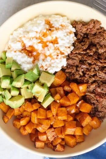 Viral hot honey ground beef bowls with seasoned beef, roasted sweet potatoes, diced avocado and hot honey drizzled on top.