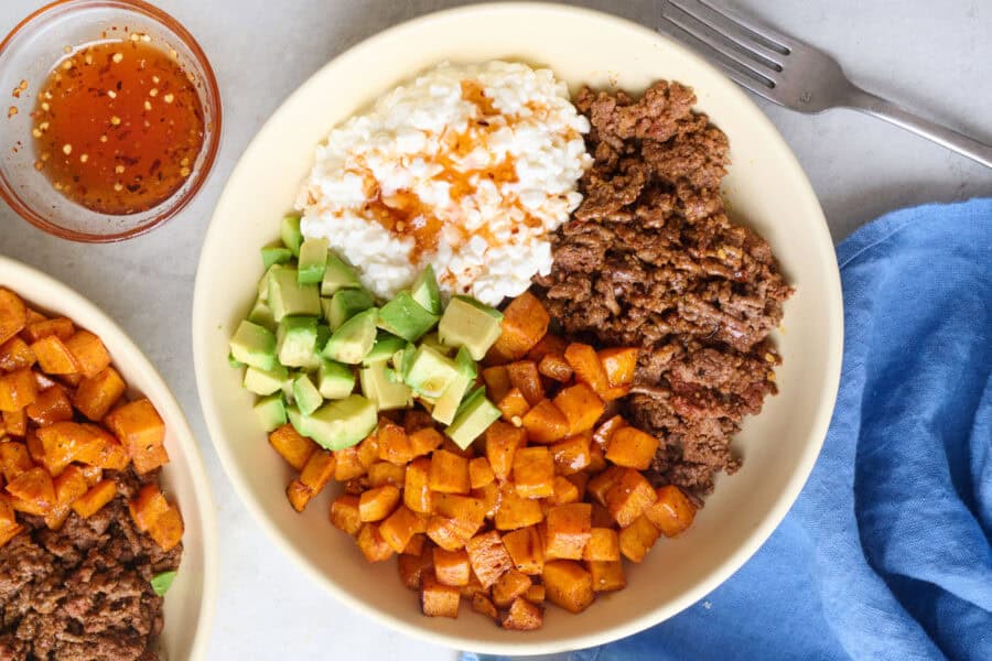 Viral hot honey ground beef bowls with seasoned beef, roasted sweet potatoes, diced avocado and hot honey drizzled on top.