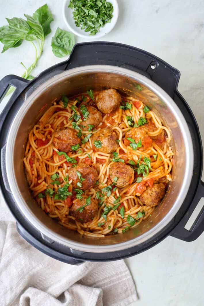 Spaghetti and meatballs recipe in an Instant Pot, garnished with fresh parsley.