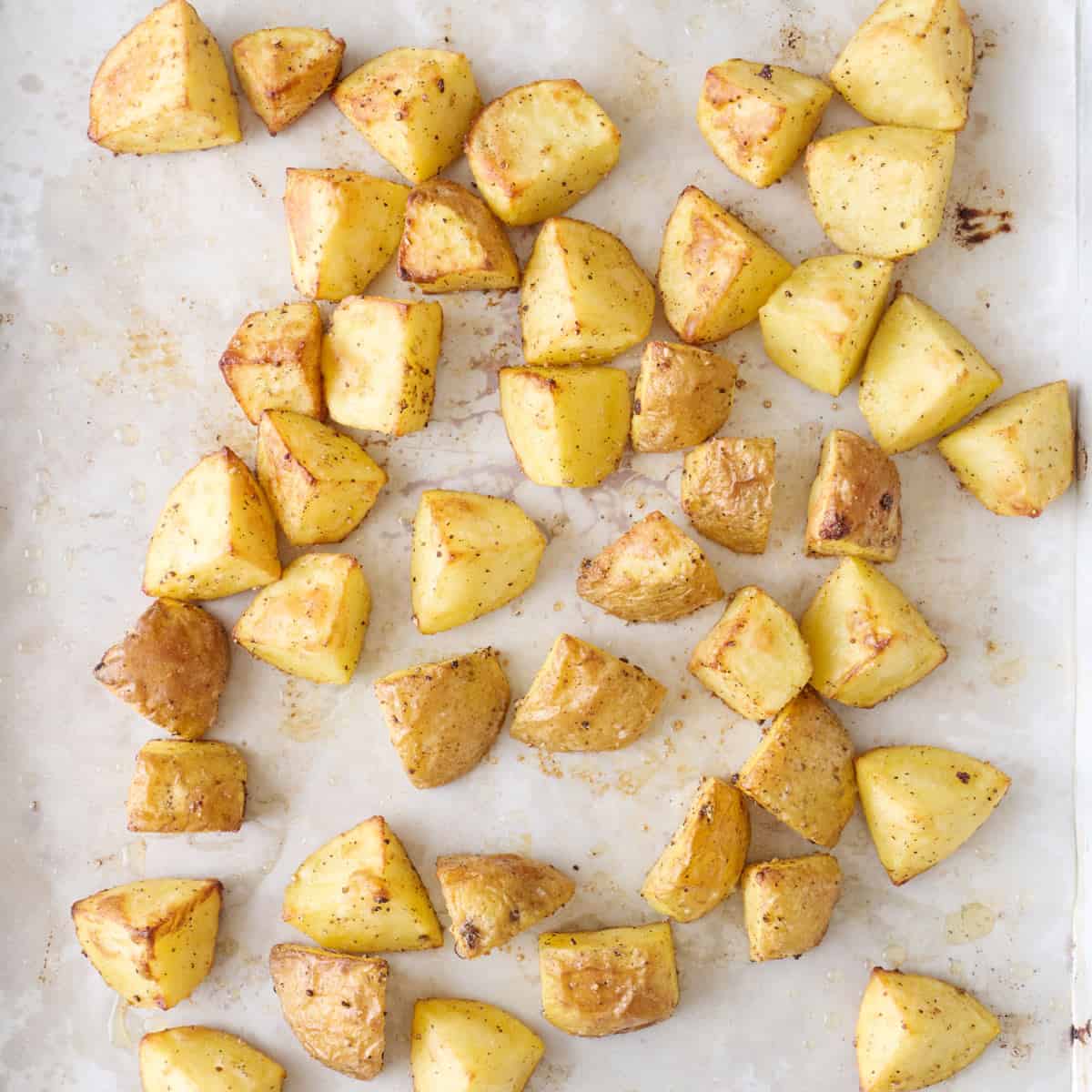 Diced potatoes on a parchment lined sheet pan after roasting.