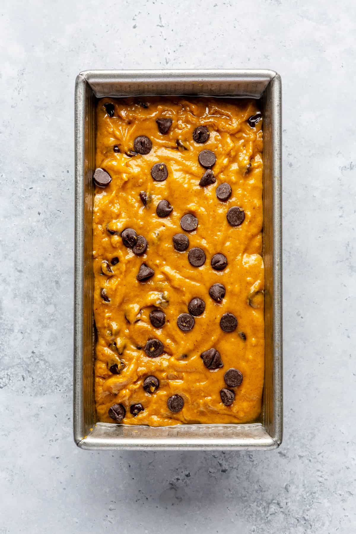 Pumpkin quick bread in a loaf pan with chocolate chips before baking.