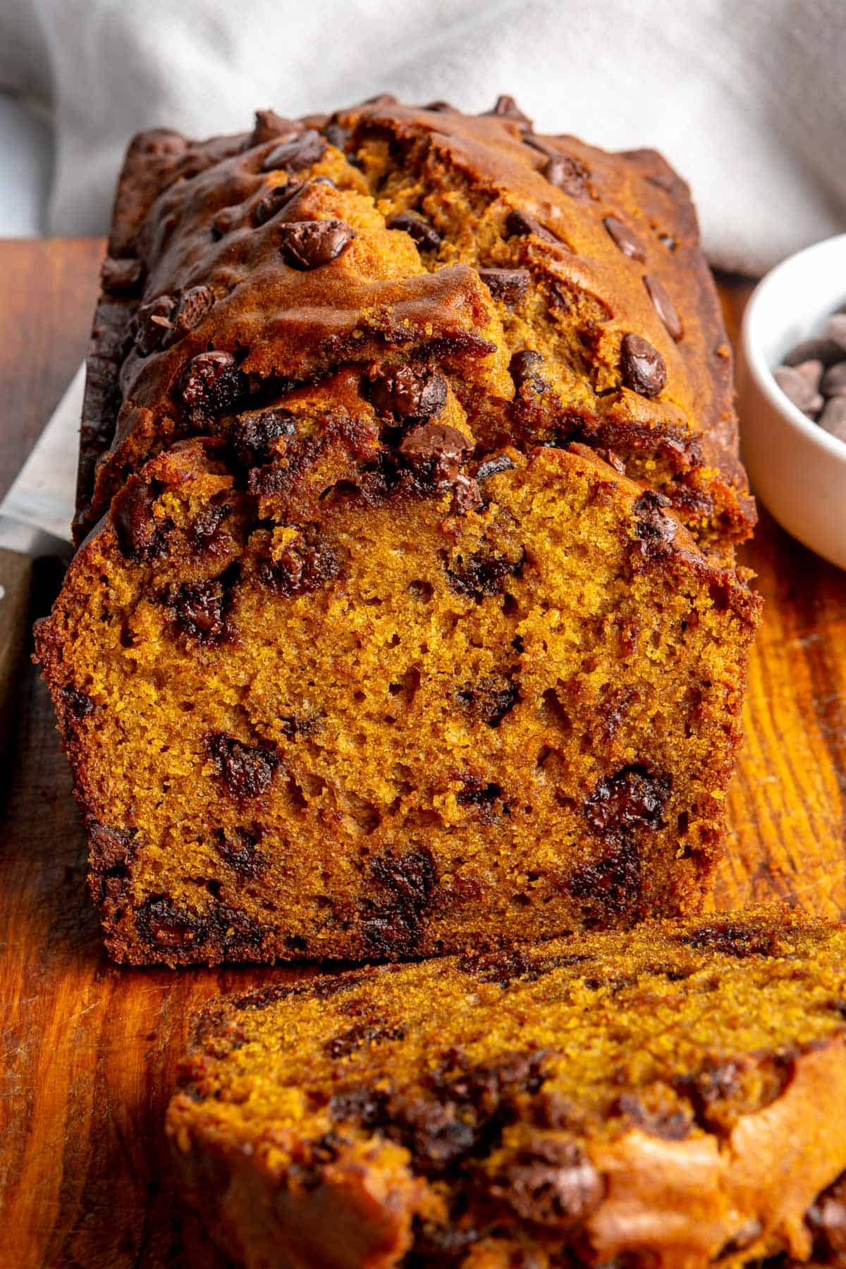 Pumpkin chocolate chip bread on a cutting board with a few slices cut, showing inside texture.