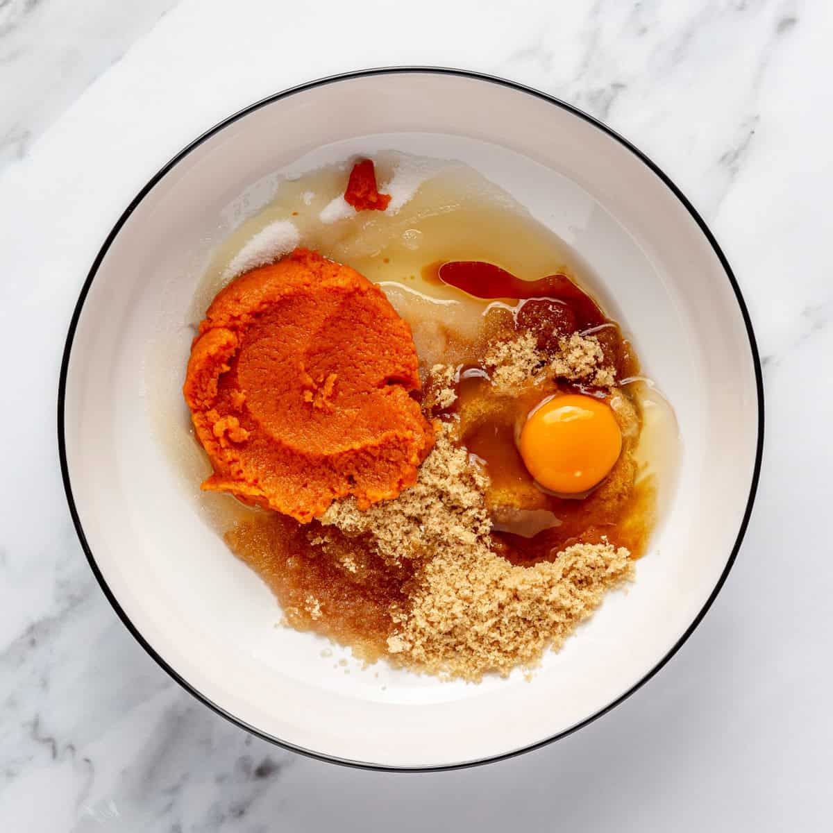 Wet ingredients and sugars in a bowl before mixing.