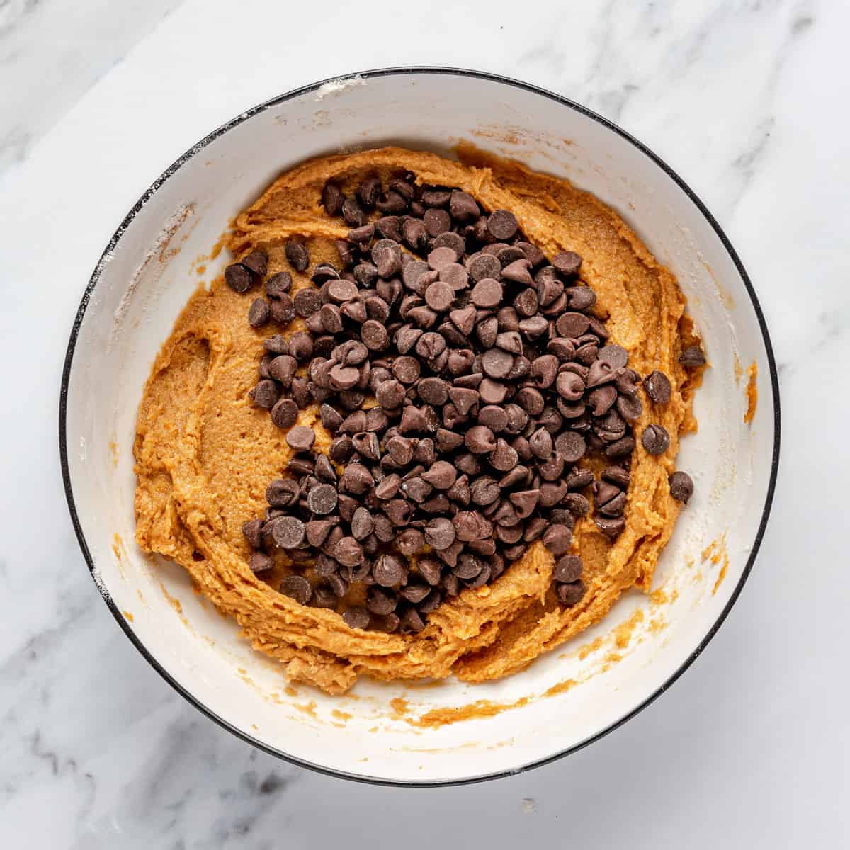 Chocolate chips on top of pumpkin cookie dough before mixing.