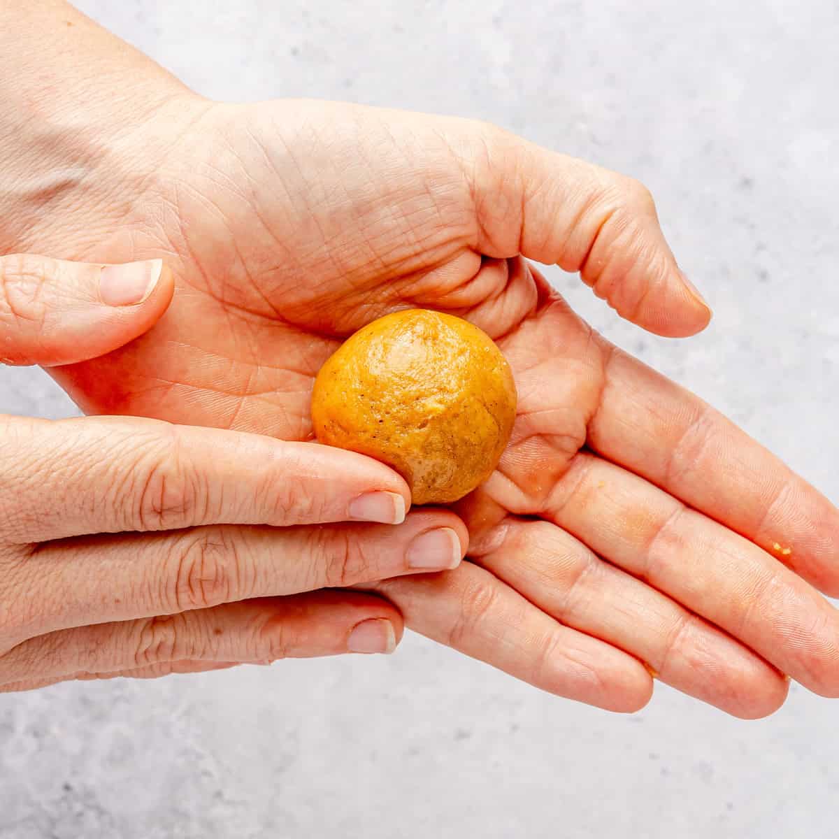 Rolling a cookie dough balls in hands.