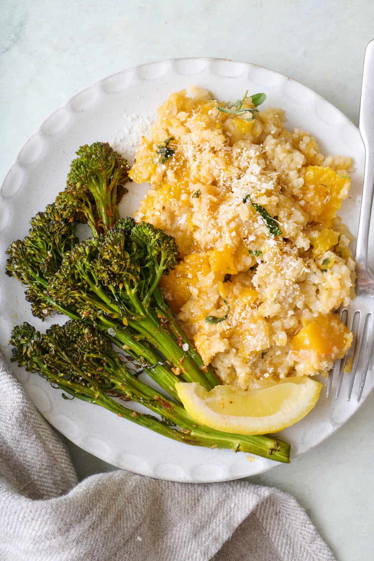 Roasted broccoli on a plate with butternut squash risotto.