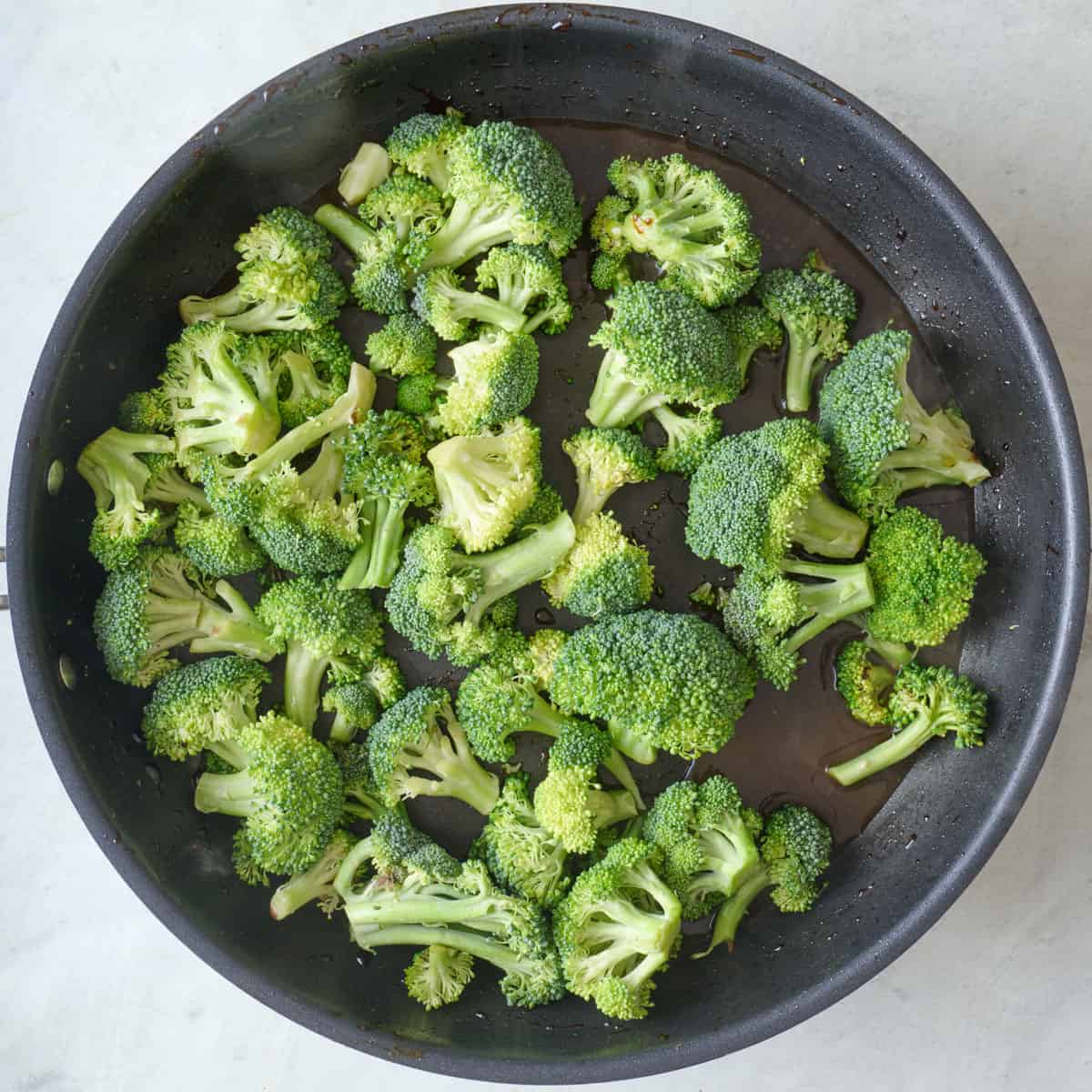 Broccoli and sauce in a skillet before cooking.