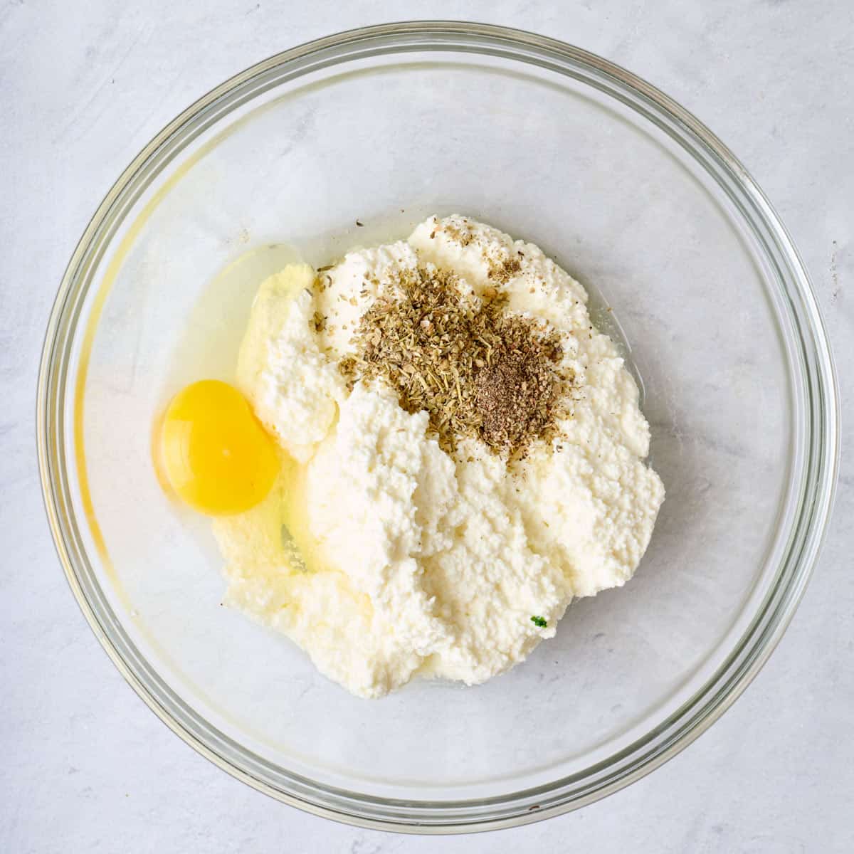 Ricotta, egg, and seasonings added to a bowl.