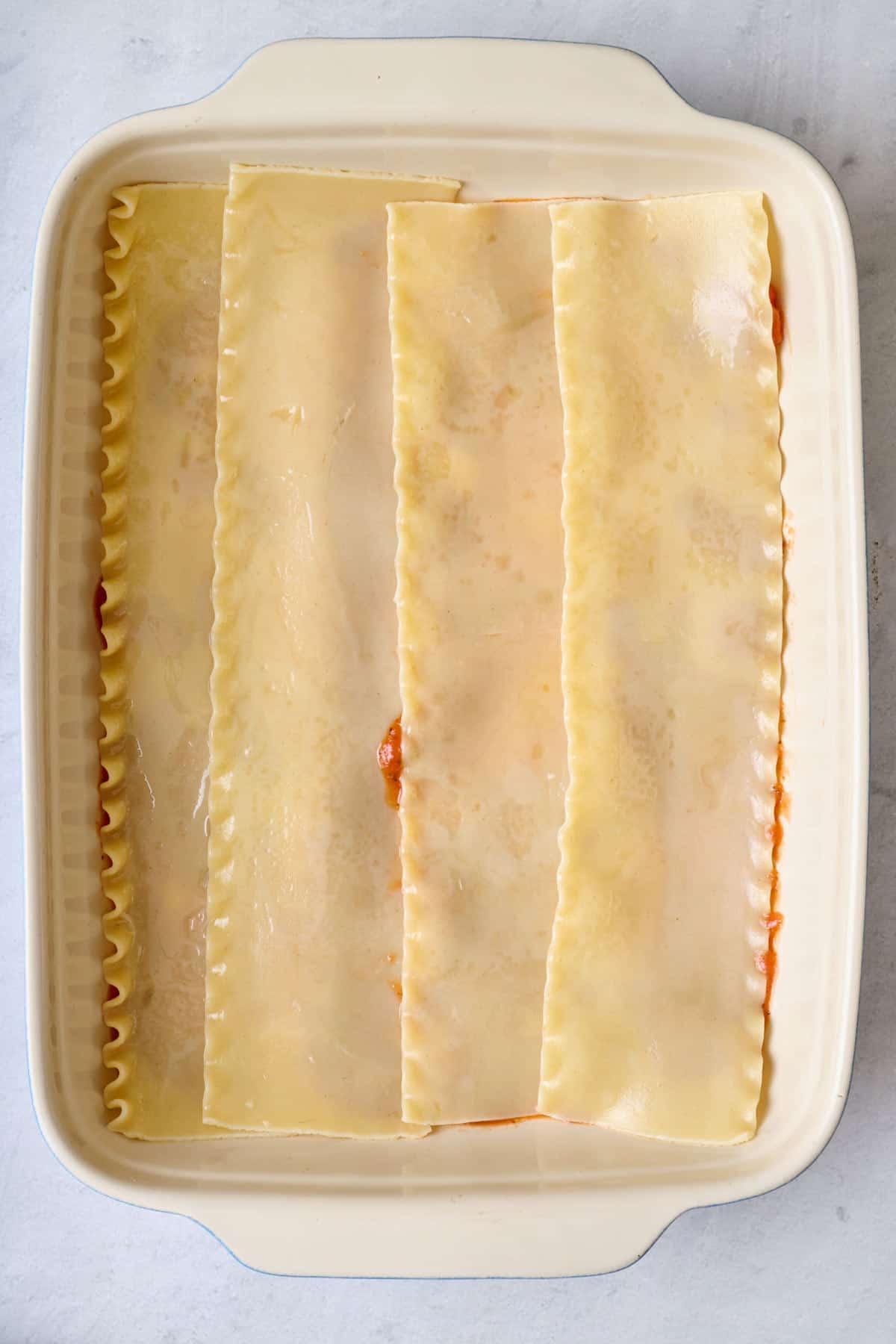 Par cooked lasagna sheet on top of sauce in baking dish.