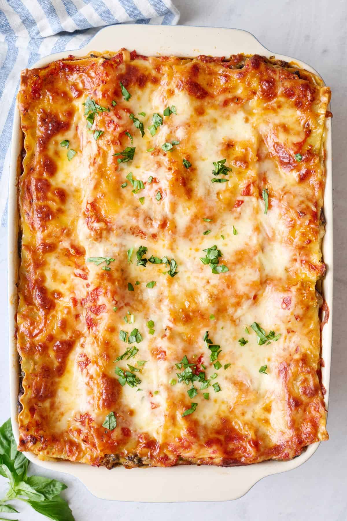 Vegetable lasagna in baking dish garnished with fresh basil.