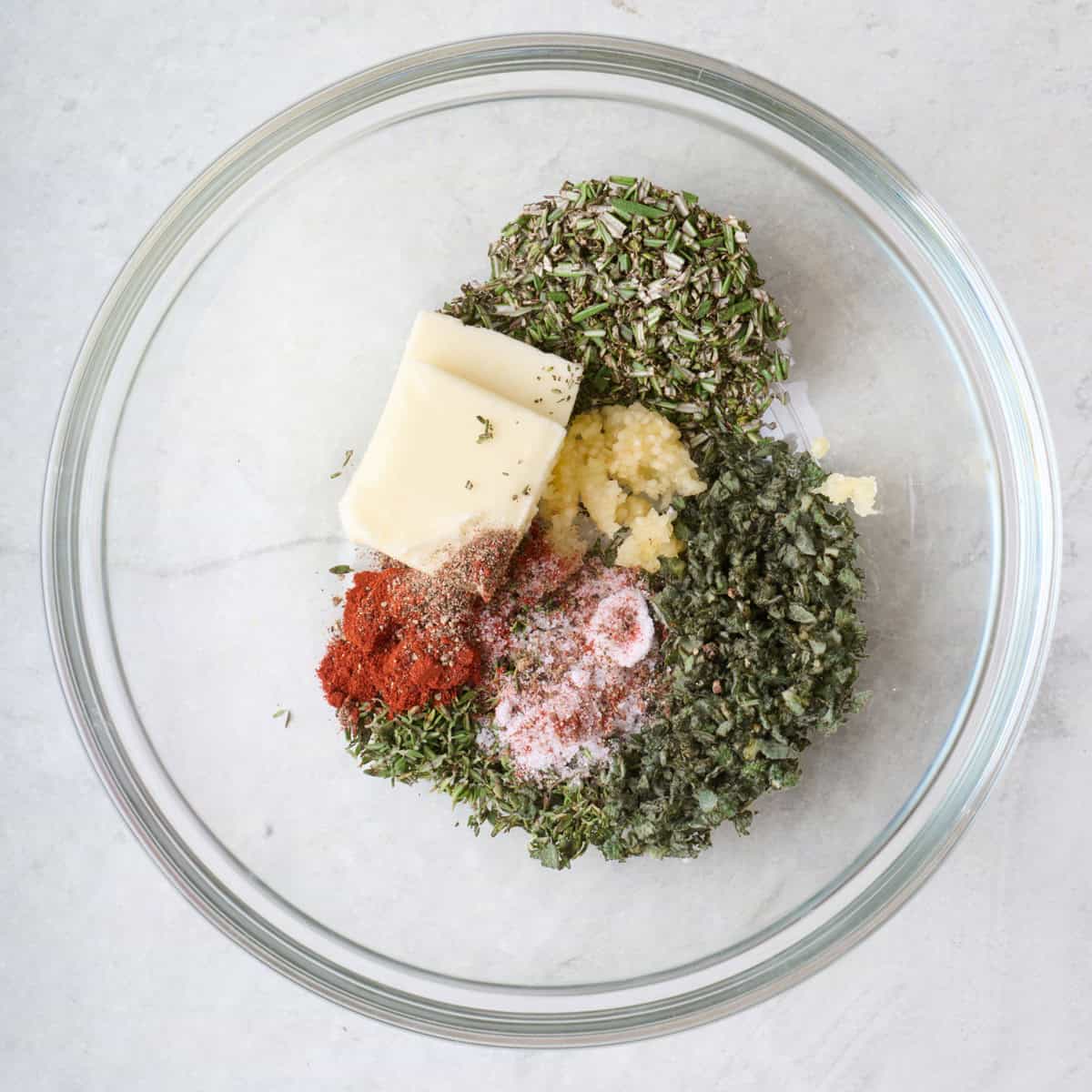 Butter, herbs, garlic and spices in a bowl.