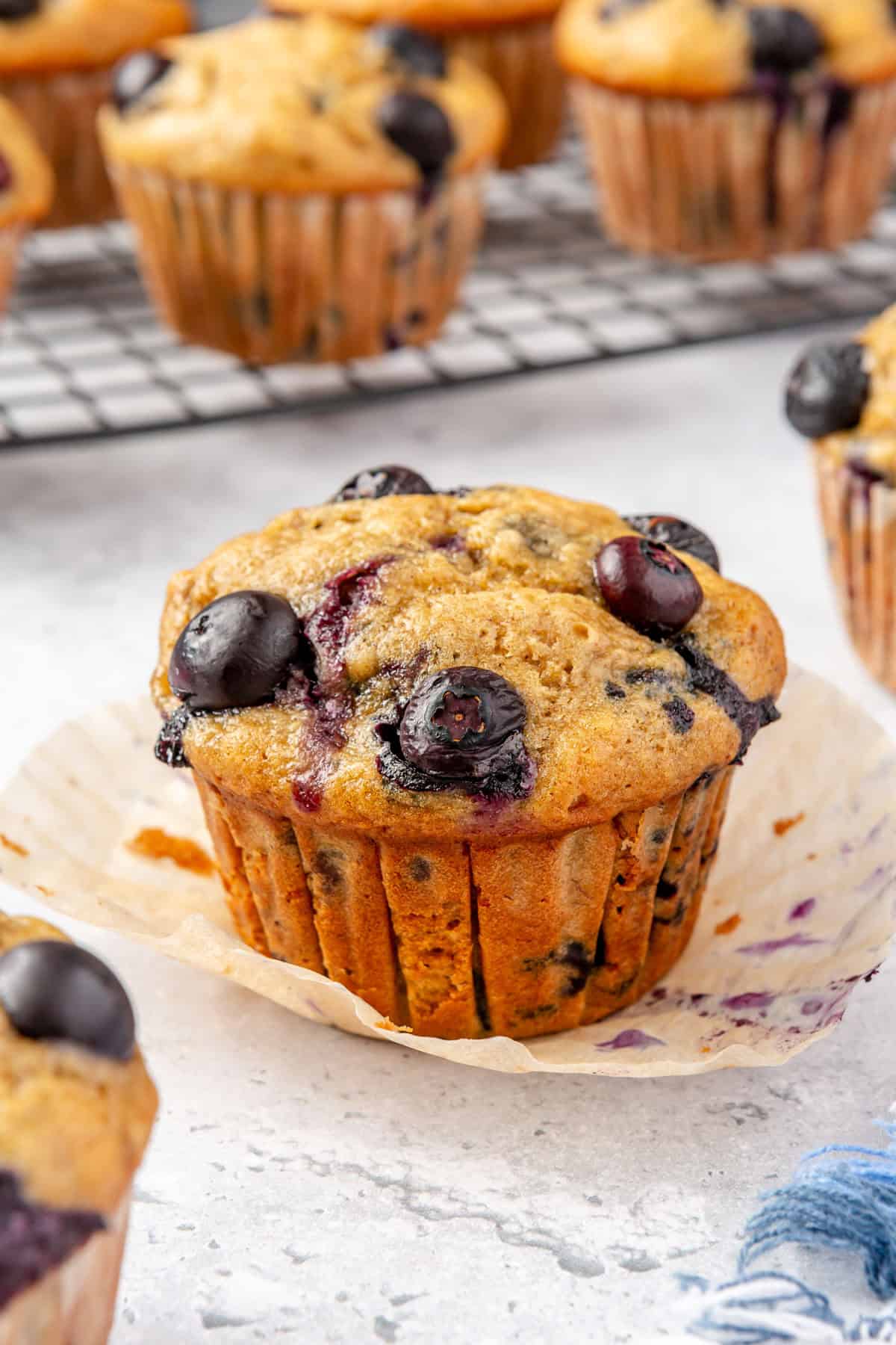 Close up on a blueberry banana muffin with paper liner peeled back.