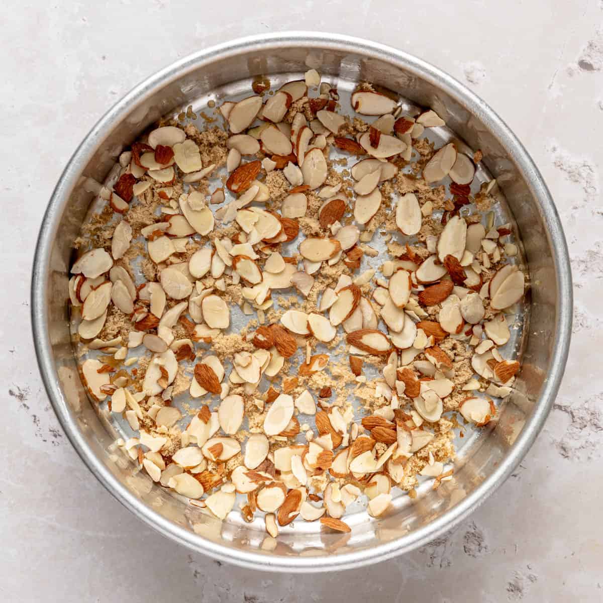 Sliced almonds and brown sugar sprinkled on the bottom of a bake pan.