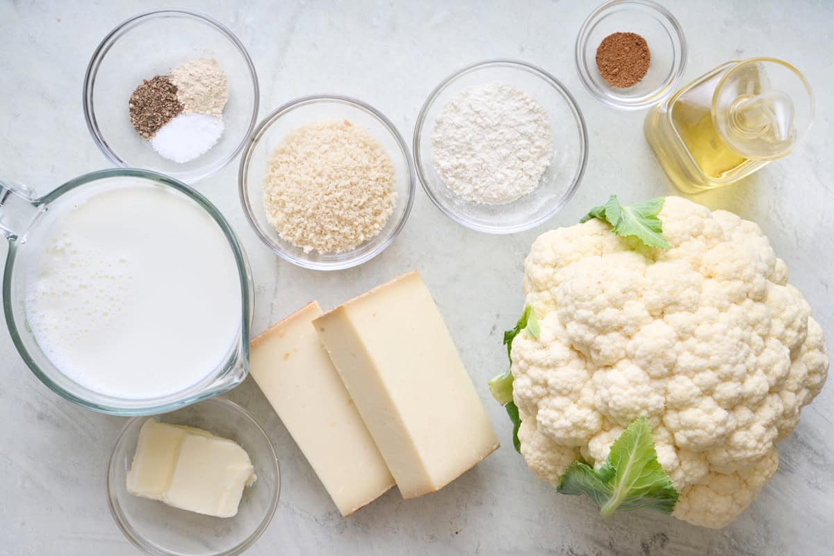 Ingredients for recipe: milk, seasonings, breadcrumbs, flour, butter, cheese, cauliflower, and oil.