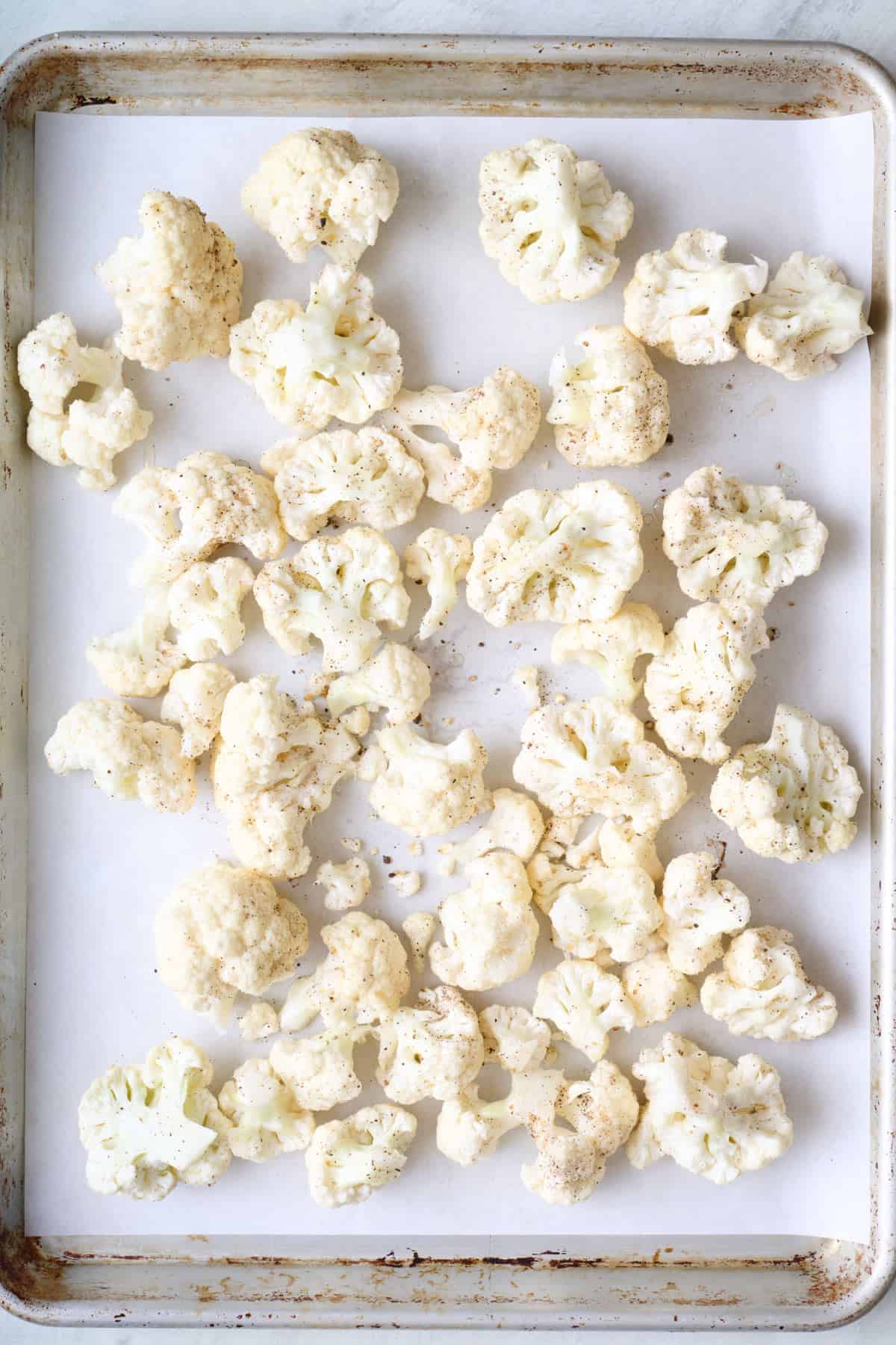 Cauliflower florets on a sheet pan before roasting.