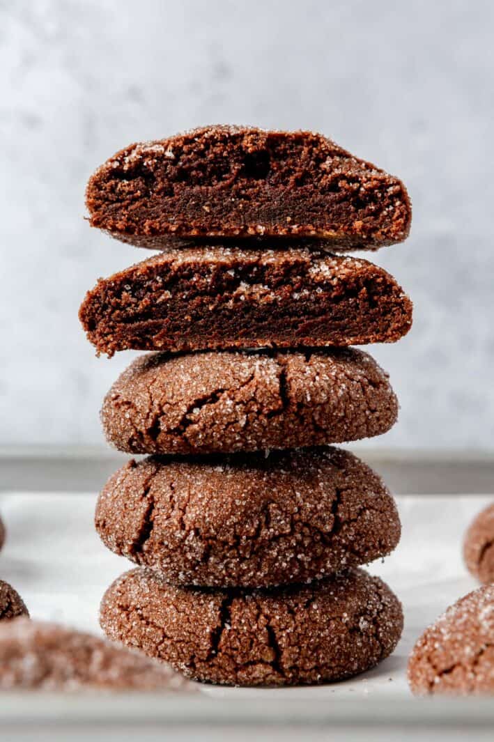 Stack of chocolate sugar cookies with one halved and cut forward to show texture.