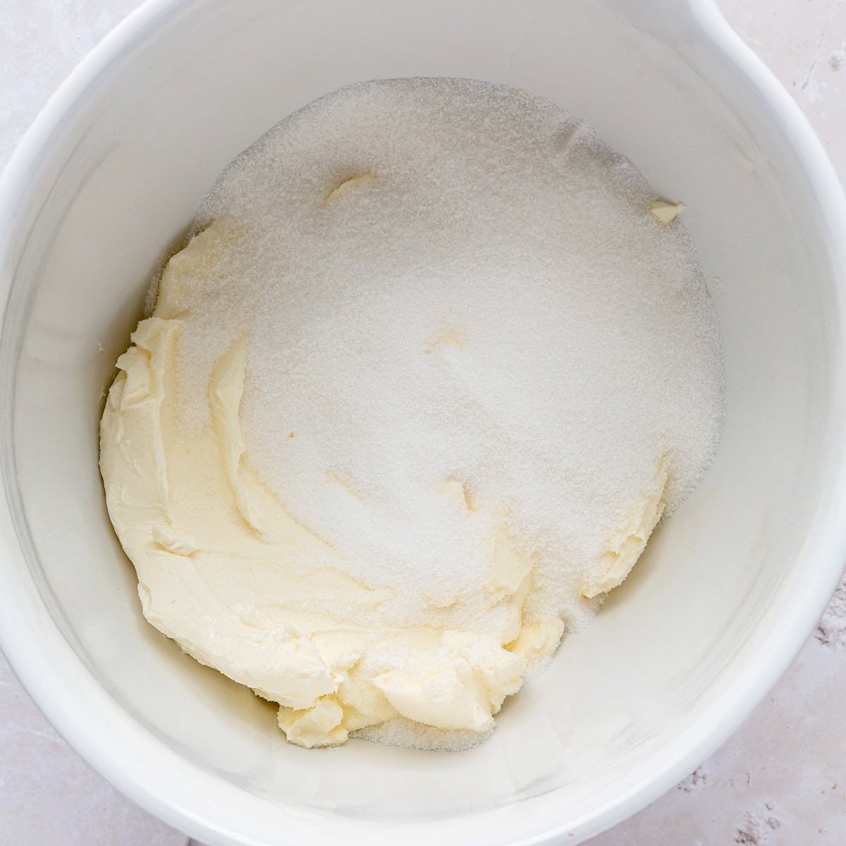 Cream cheese and sugar in bowl of stand mixer.