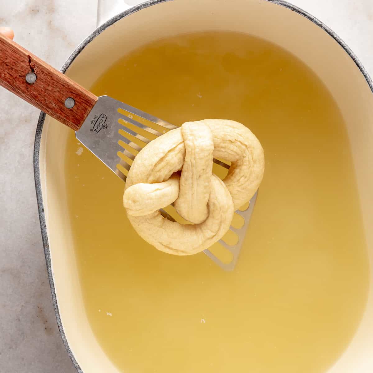 Dipping pretzel into boiling baking soda water.